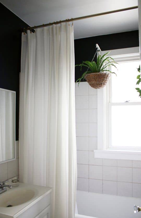 a white shower curtain over a small bath space in a small bathroom