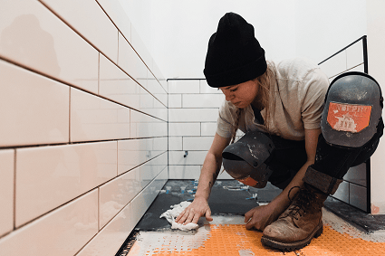 A woman removing the flooring during a bathroom renovation