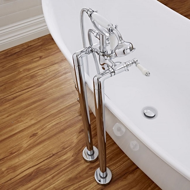 Chrome freestanding-bath-tap with white tap handles and traditional shower handset over a freestanding bath