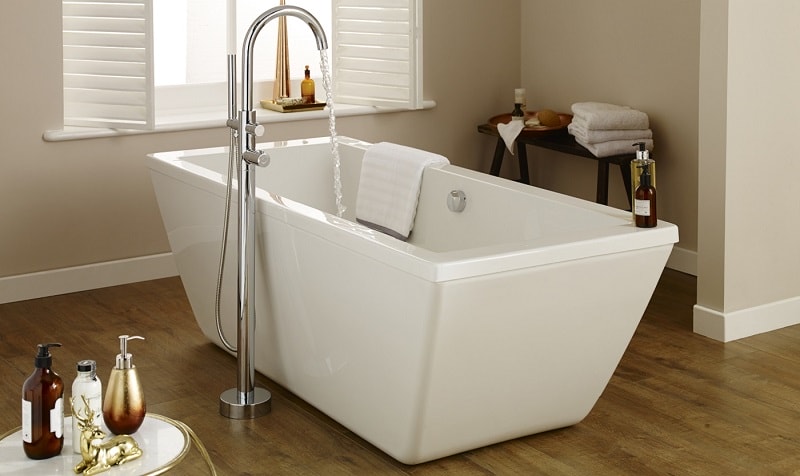 White rectangular freestanding bath in a neutral white and wood bathroom
