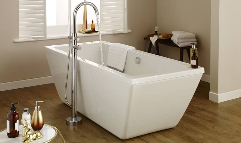 White rectangular freestanding bath in a neutral white and wood bathroom