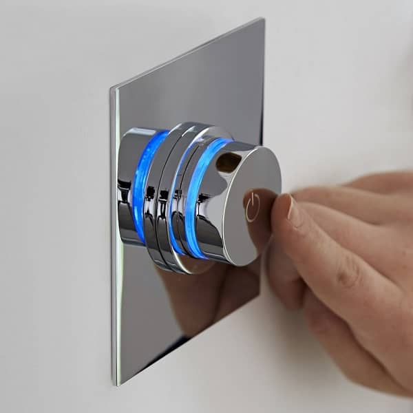 Blue illuminated digital shower push button control being pressed