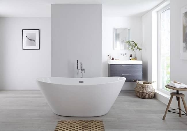 Modern curved freestanding bath in the middle of a large minimalist bathroom with vanity unit and mirror cabinet