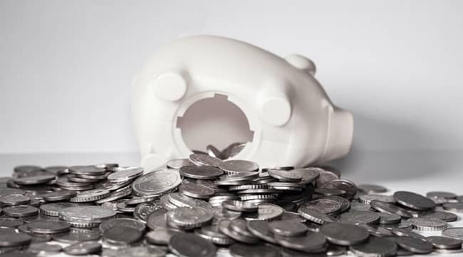 Open piggy bank with silver coins spilling out