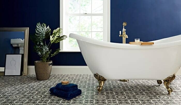A white freestanding bathtub and gold bath tap in a blue bathroom