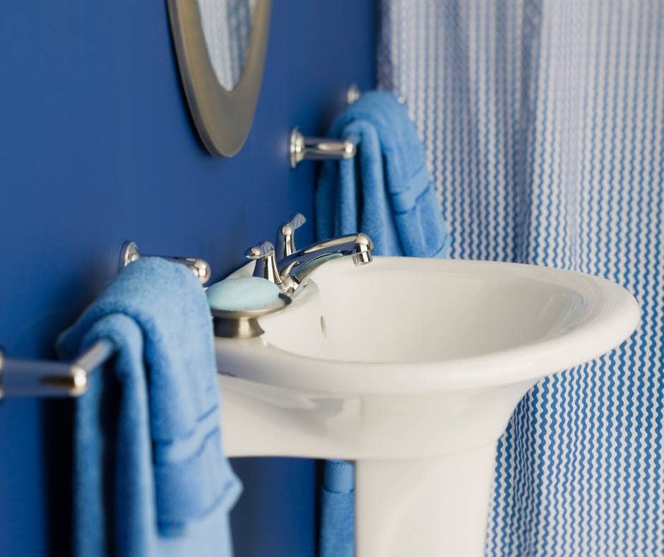 Blauwe muren Blauwe muren in een badkamer met een witte wastafel en chromen kranen
