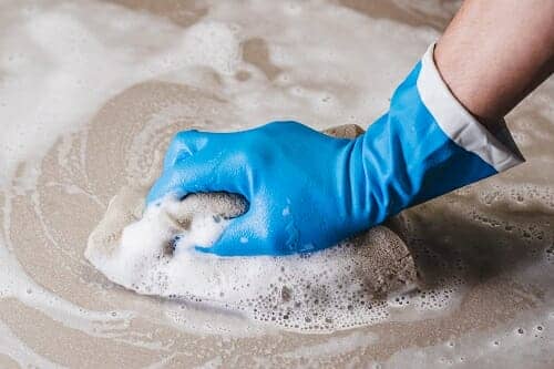 a hand scrubbing the floor in a bathroom with a sponge