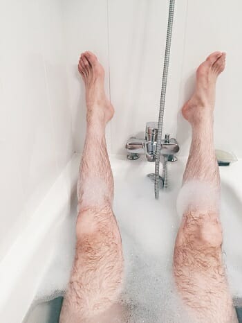 amn in a bath tub with his legs in the air amn in a bath tub with his legs in the air