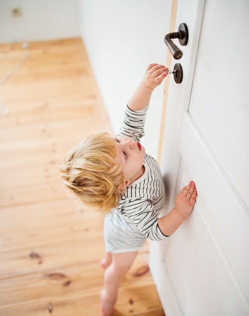 Toddler child in a dangerous situation at home. toddler opening a bathroom door