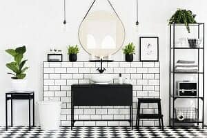 Mirror between plants above black washbasin in bathroom interior