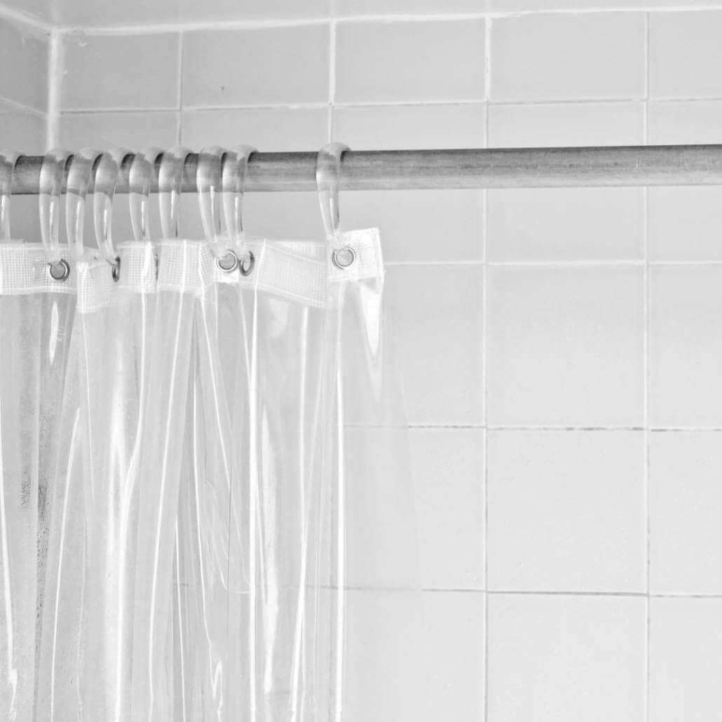 Clear shower curtain in front of white shower wall