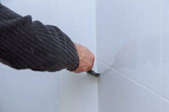 Worker repairing bathroom wall tiling using trowel