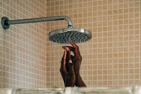 Female hands visible in shower enclosure directly beneath shower flow