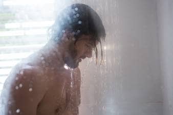 Man taking a shower in bathroom