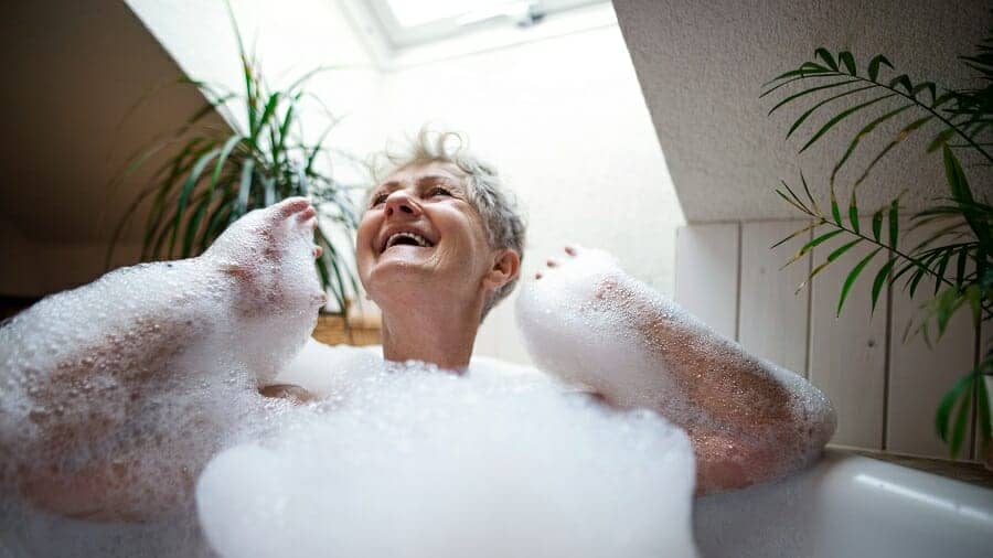 Vrolijke senior vrouw wassen in een bubbelbad