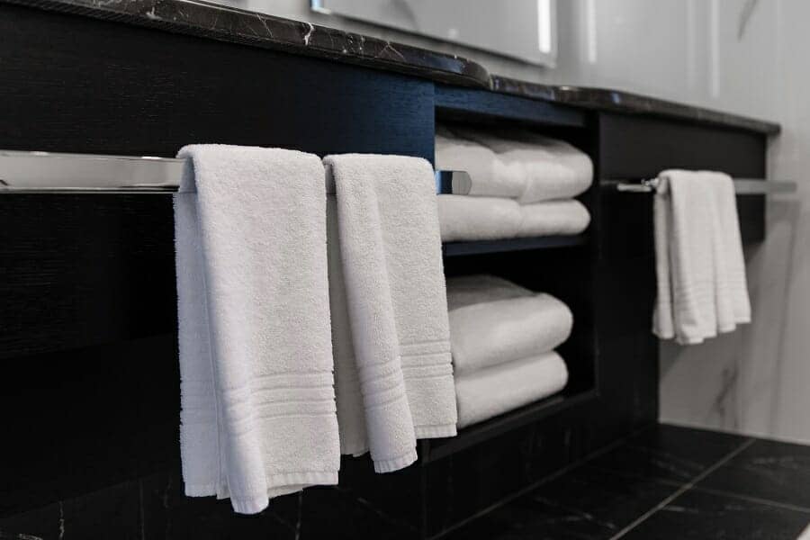 White bathroom towels stored in a modern black monochrome bathroom ensuite