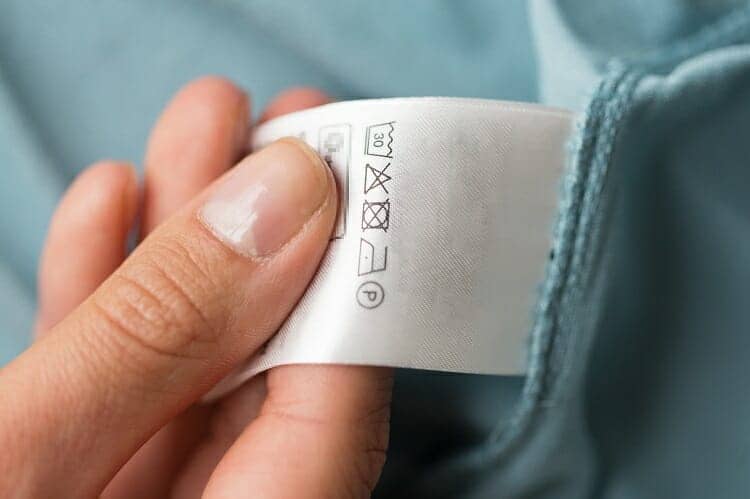 a hand holding a care label on a bathmat