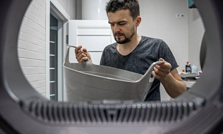 Portrait of a man, view from the washing machine, loading and washing a dirty bathmat