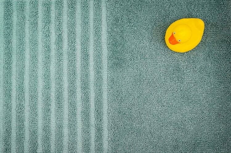 A bathmat with a yellow rubber duck on it