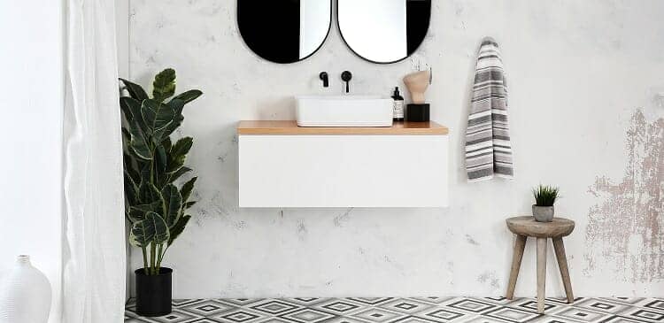 A white vanity unit and black taps on a white bathroom wall