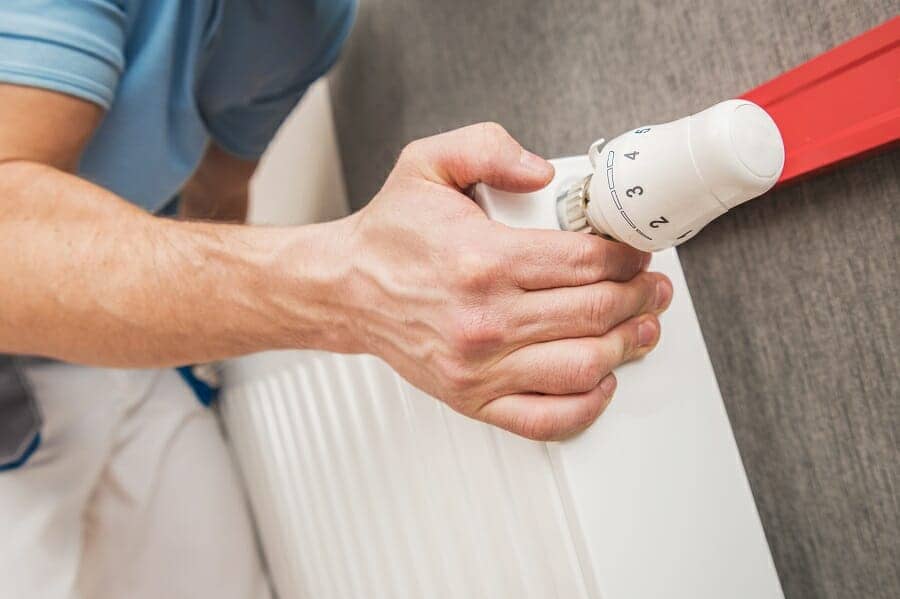 Traditional convector radiator being fitted by plumber