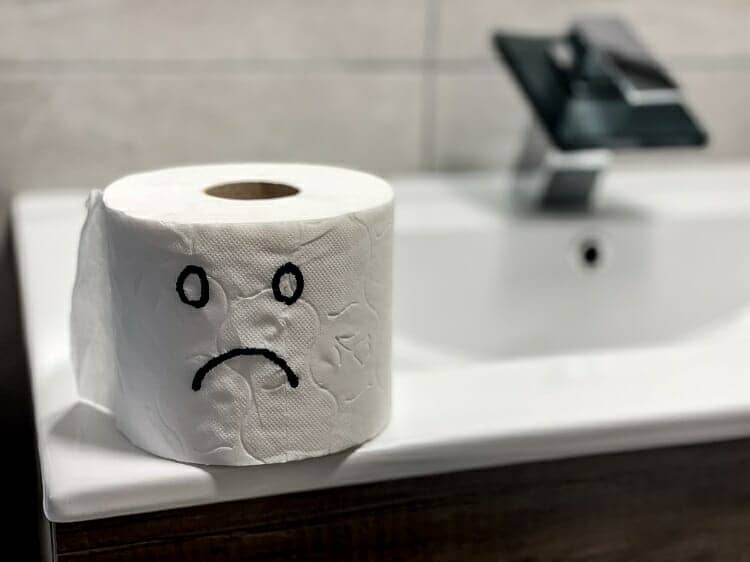 A sad face drawn on a roll of toilet paper. 